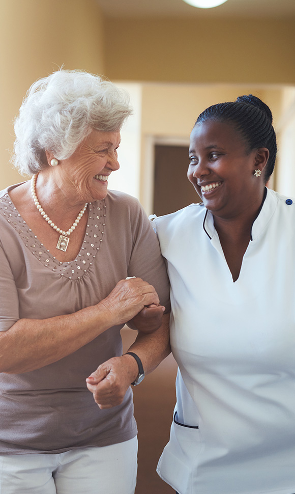 smiling nurse assisting elderly woman in hallway two people in healthcare setting enjoying companionship and shared moments 7 smiles 7 connections