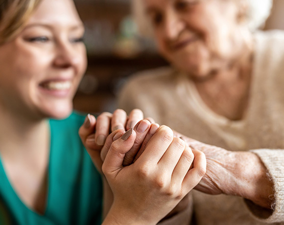 caregiver holding hands with elderly person showing connection and compassion in supportive setting
